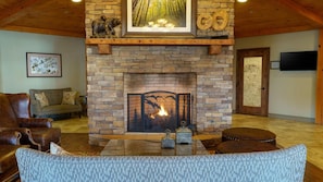 A cozy living room with a stone fireplace, leather furniture, and a framed picture above the mantel.