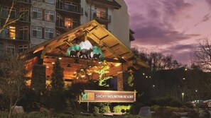 Smoky Mountain Resort mit einem gut sichtbaren Logo eines Bären auf dem Dach, umgeben von gepflegten Gärten und einem mehrstöckigen Gebäude im Hintergrund.