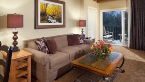 A living room with a sofa, a coffee table with flowers, a lamp, and a framed picture on the wall.
