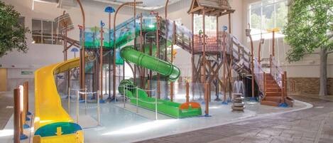 Un parque acuático interior con toboganes y estructuras para escalar.