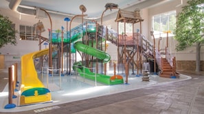 An indoor water park with slides and climbing structures.