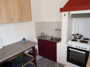 Une cuisine de taille réduite, équipée d’une cuisinière, d’un évier et de meubles de rangement en bois.