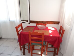 A dining area with a table set for four, featuring a red tablecloth, a glass bowl, and placemats.
