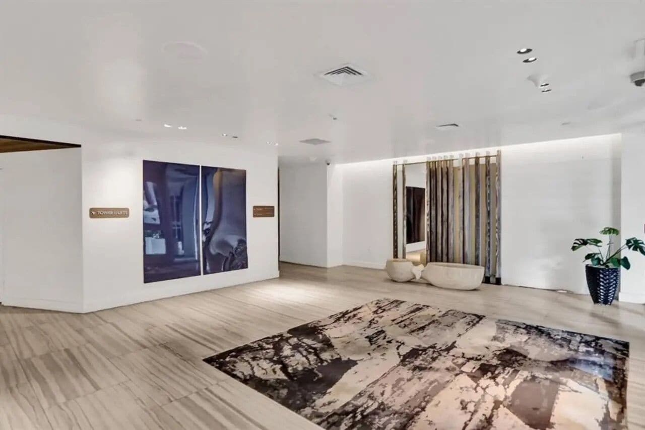 A modern interior with a large abstract painting, a patterned rug, and a potted plant.