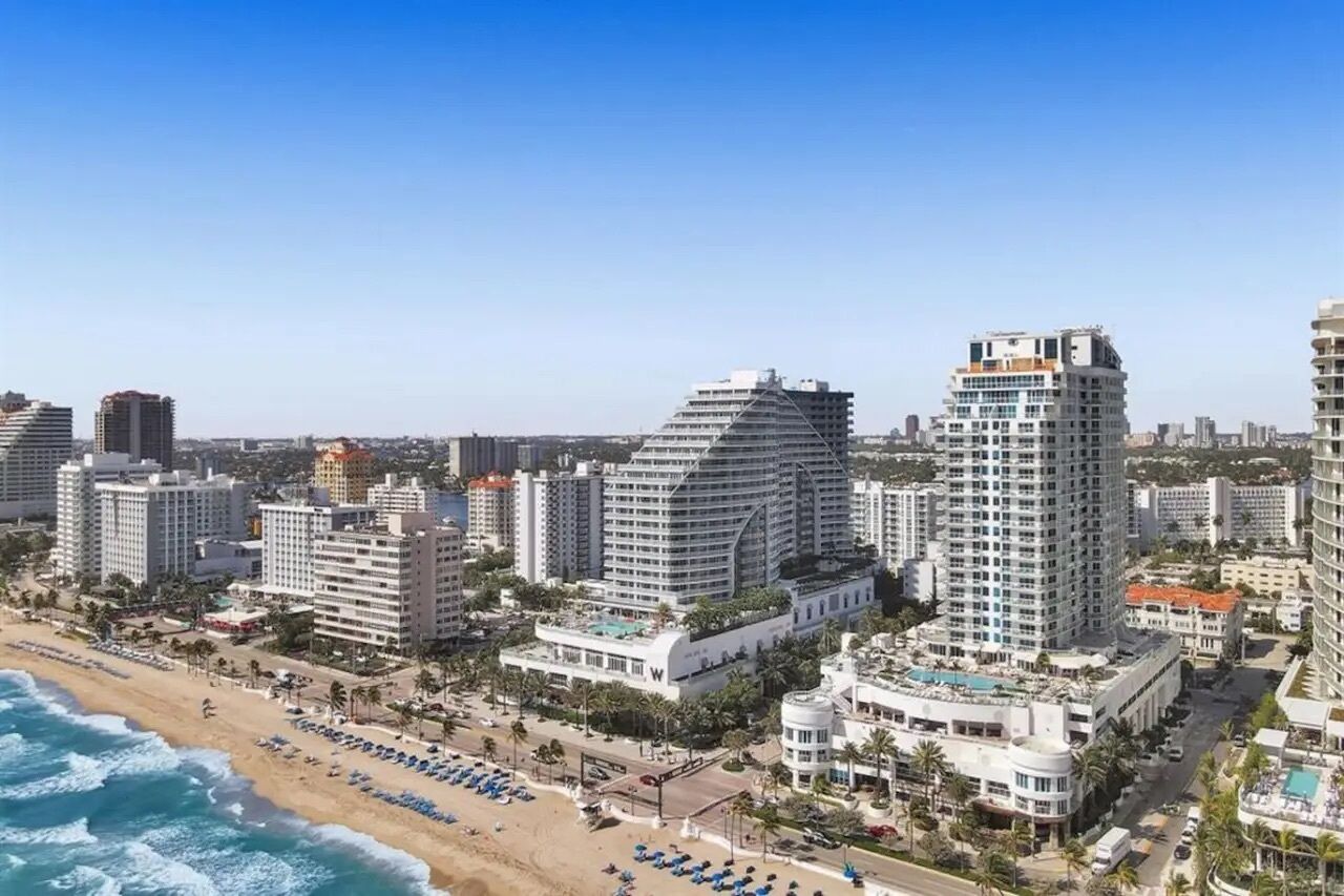 Un paysage urbain côtier avec de grands hôtels, une plage et un ciel dégagé.