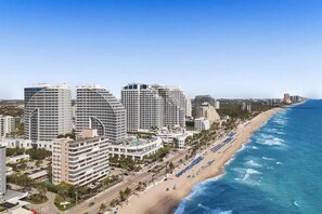 Un paysage urbain côtier avec de grands hôtels, une plage et un ciel bleu dégagé.