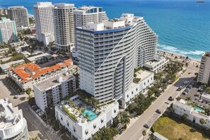 A high-rise hotel with multiple floors, a curved facade, and a pool area. - 18th Floor Luxury W Residence - 2 King Suites, Pools & 2-min walk to Beach (Fort Lauderdale)