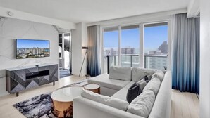 Ein modernes Wohnzimmer mit großem Fenster, Flachbildfernseher, Sofa und Seitentisch.