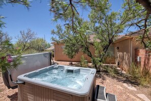 Un bain à remous installé à l’extérieur, avec une maison en arrière-plan.