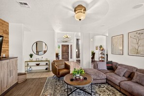 Ein modernes Wohnzimmer mit Sofa, Sessel, Couchtisch und Kamin.