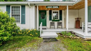 A guest room with a porch, a green door, and a sign indicating 'GUEST ROOMS'.