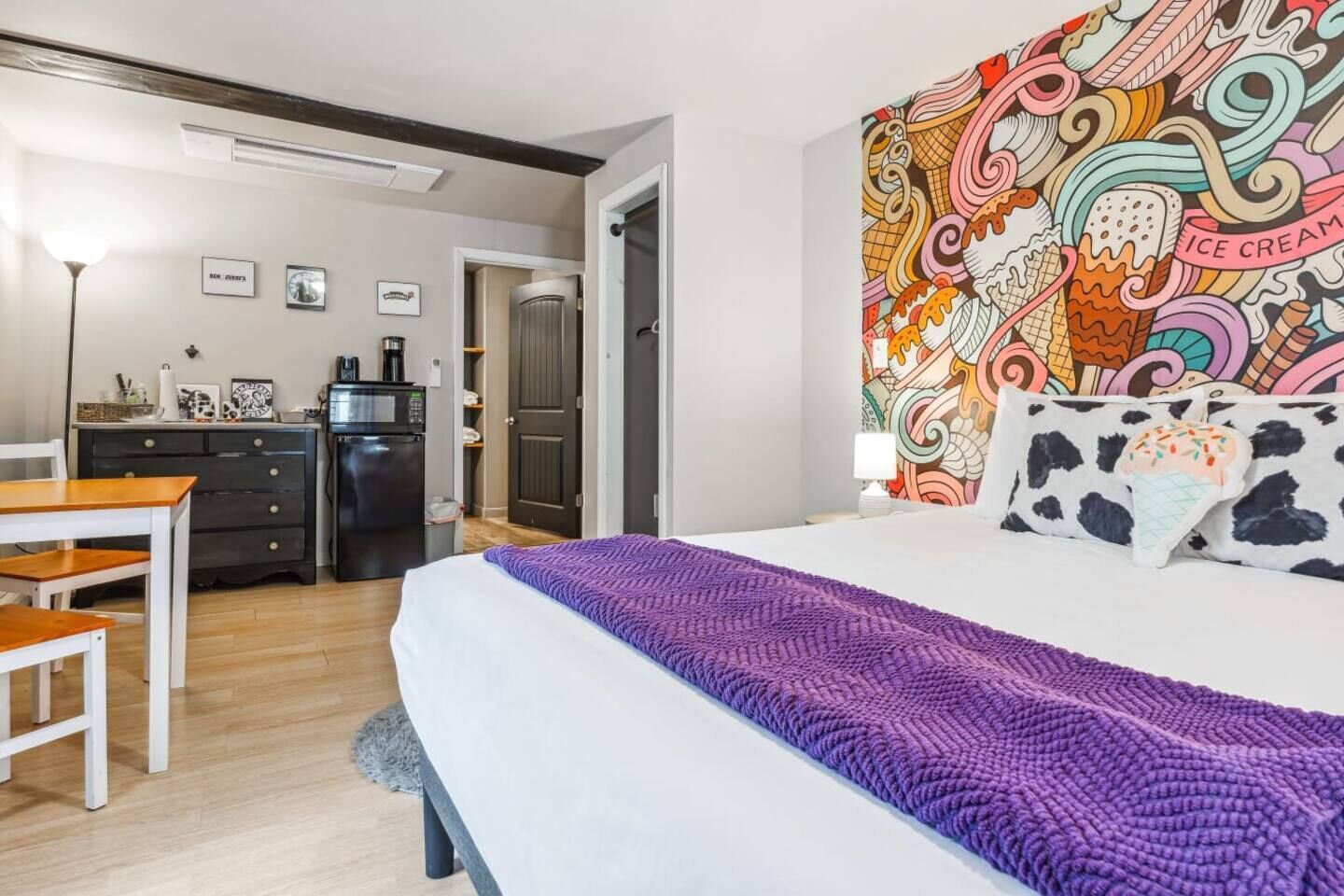 A hotel room with a bed, a desk, a refrigerator, and a microwave.