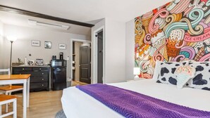 A hotel room with a bed, a desk, a refrigerator, and a microwave.