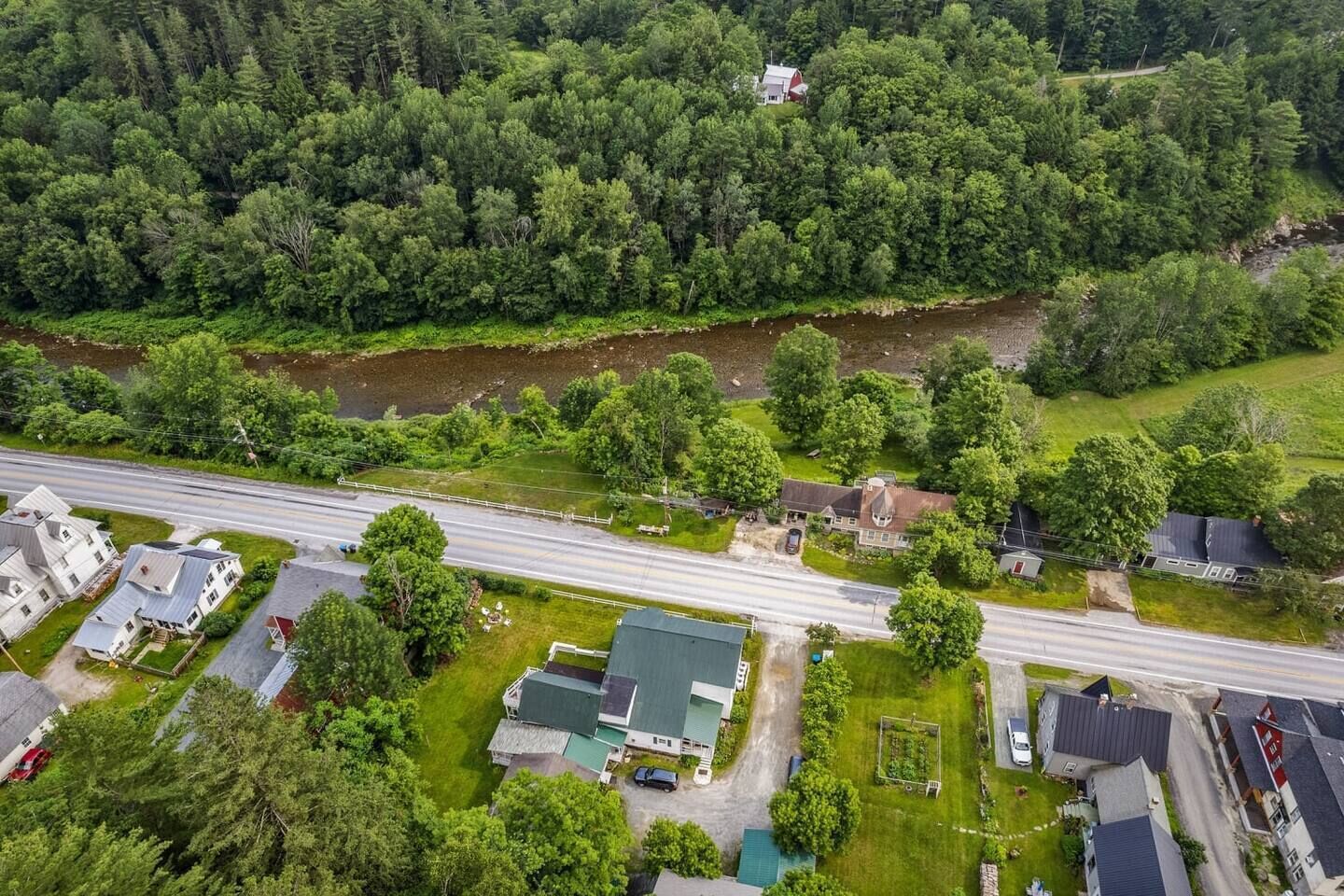 An aerial view of a residential area with houses, a road, and a river.