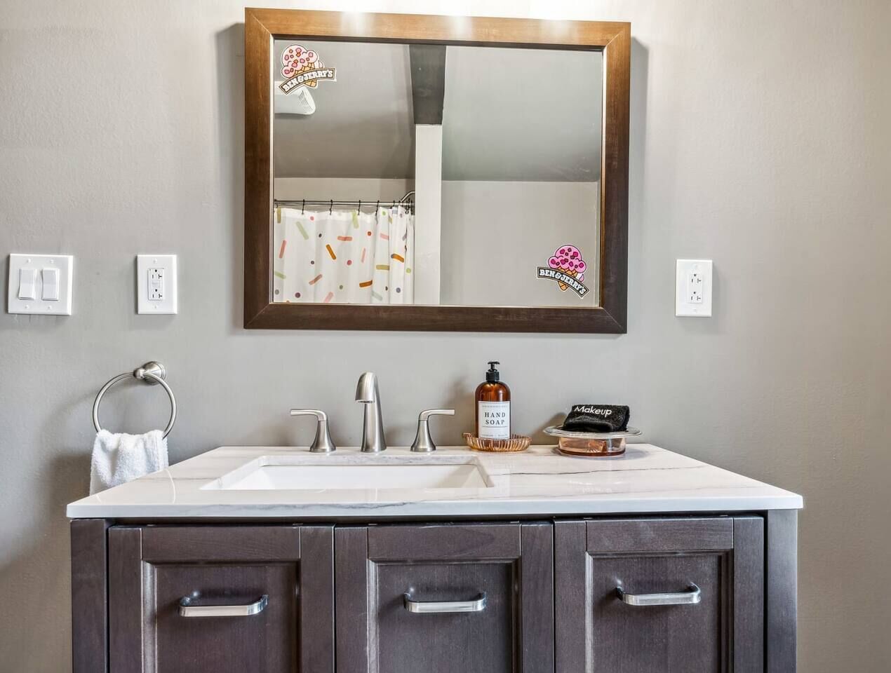 A bathroom with a double sink vanity, a mirror, and a towel rack.