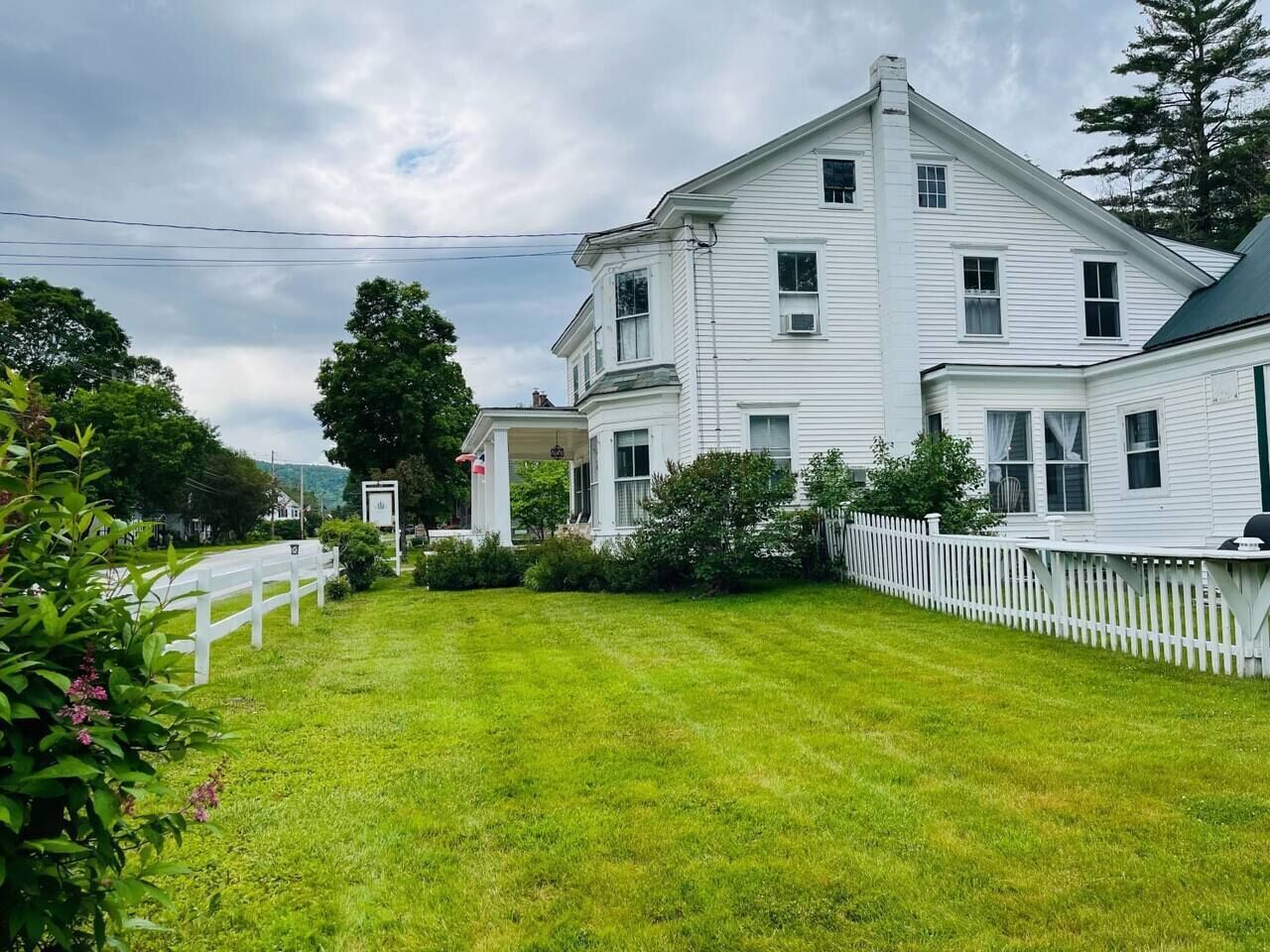 A two-story white house with a front porch and a white picket fence.