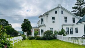 A two-story white house with a front porch and a white picket fence.