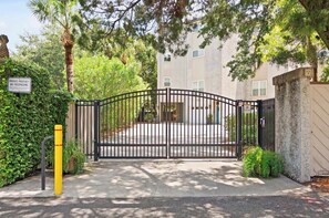 Une entrée fermée par un portail, menant à un bâtiment sur lequel est apposée une pancarte indiquant « PROPRIÉTÉ PRIVÉE, DÉFENSE D’ENTRER », le tout étant entouré de verdure et d’arbres.