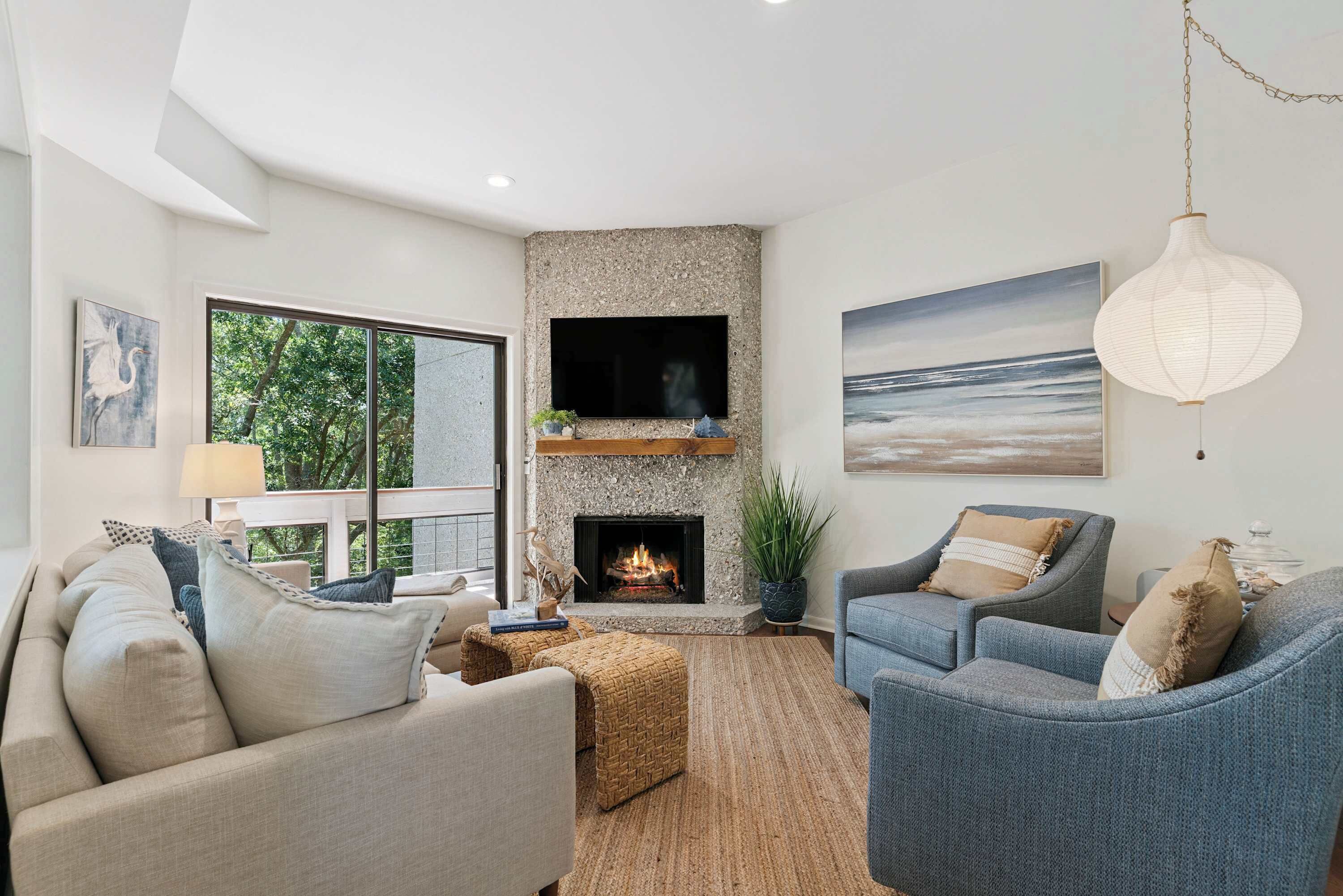A modern living room with a fireplace, comfortable seating, and a view of the outdoors.