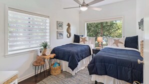 Ein Schlafzimmer mit zwei Betten, einem Deckenventilator und einem großen Fenster.
