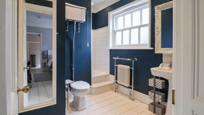Un baño con inodoro, bañera, lavabo y ventana.