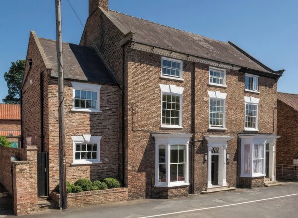 A traditional brick building with multiple windows and a corner entrance.