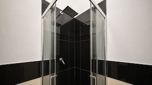 A modern bathroom with a glass-enclosed shower, black and white tiled walls, and a visible showerhead.