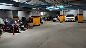 Eine mehrgeschossige Parkgarage mit verschiedenen Fahrzeugen, darunter Motorräder und Autos, sowie einem Schild für die Wasseraufbereitung.