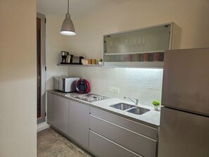 Een moderne keuken met een ingebouwde oven, een magnetron, een waterkoker en een spoelbak.