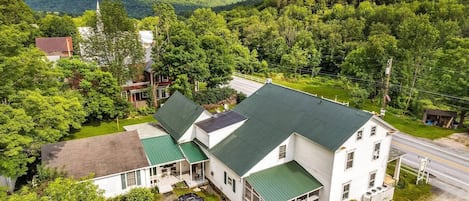 A two-story house with a green roof, a covered porch, and a driveway with a parked car.