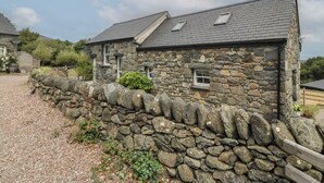 A stone house with a gravel driveway and a stone wall.