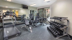 A gym with treadmills, weight machines, and dumbbells.