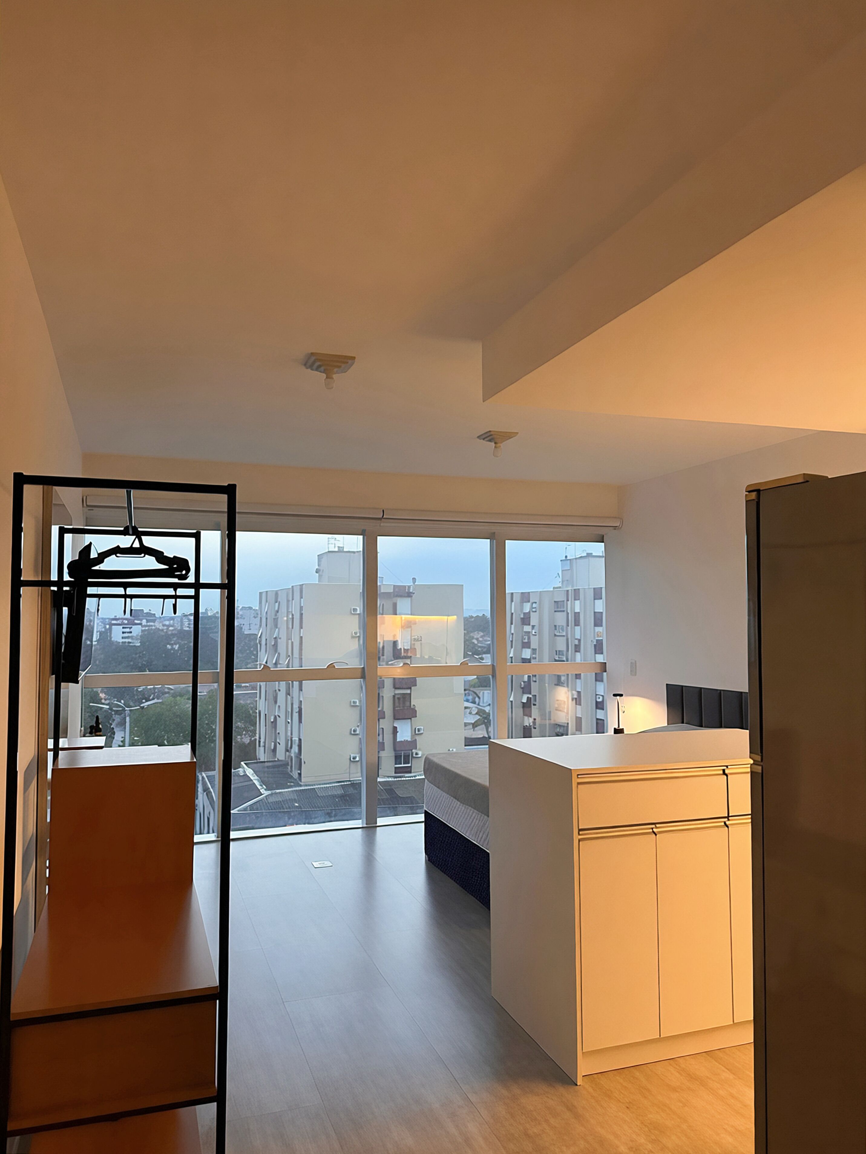 Cozinha moderna com uma janela ampla, um banco de madeira e vista para a cidade.