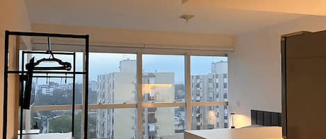 A modern kitchen with a large window, a wooden bench, and a view of the cityscape.