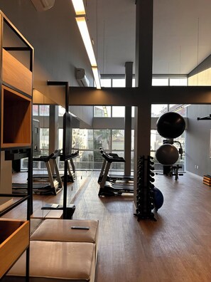 A gym with treadmills, exercise balls, and a rack of dumbbells.