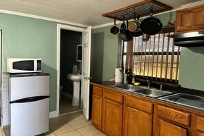 A compact kitchen with a microwave, sink, and wooden cabinets. - Apt 1br, Playgrnd, SRQ Dwntwn, Siesta Key, 20, 3ppl (Sarasota)