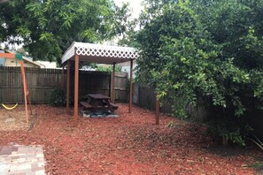 A backyard with a wooden pergola, a picnic table, and a covered seating area. - Apt 1br, Playgrnd, SRQ Dwntwn, Siesta Key, 20, 3ppl (Sarasota)