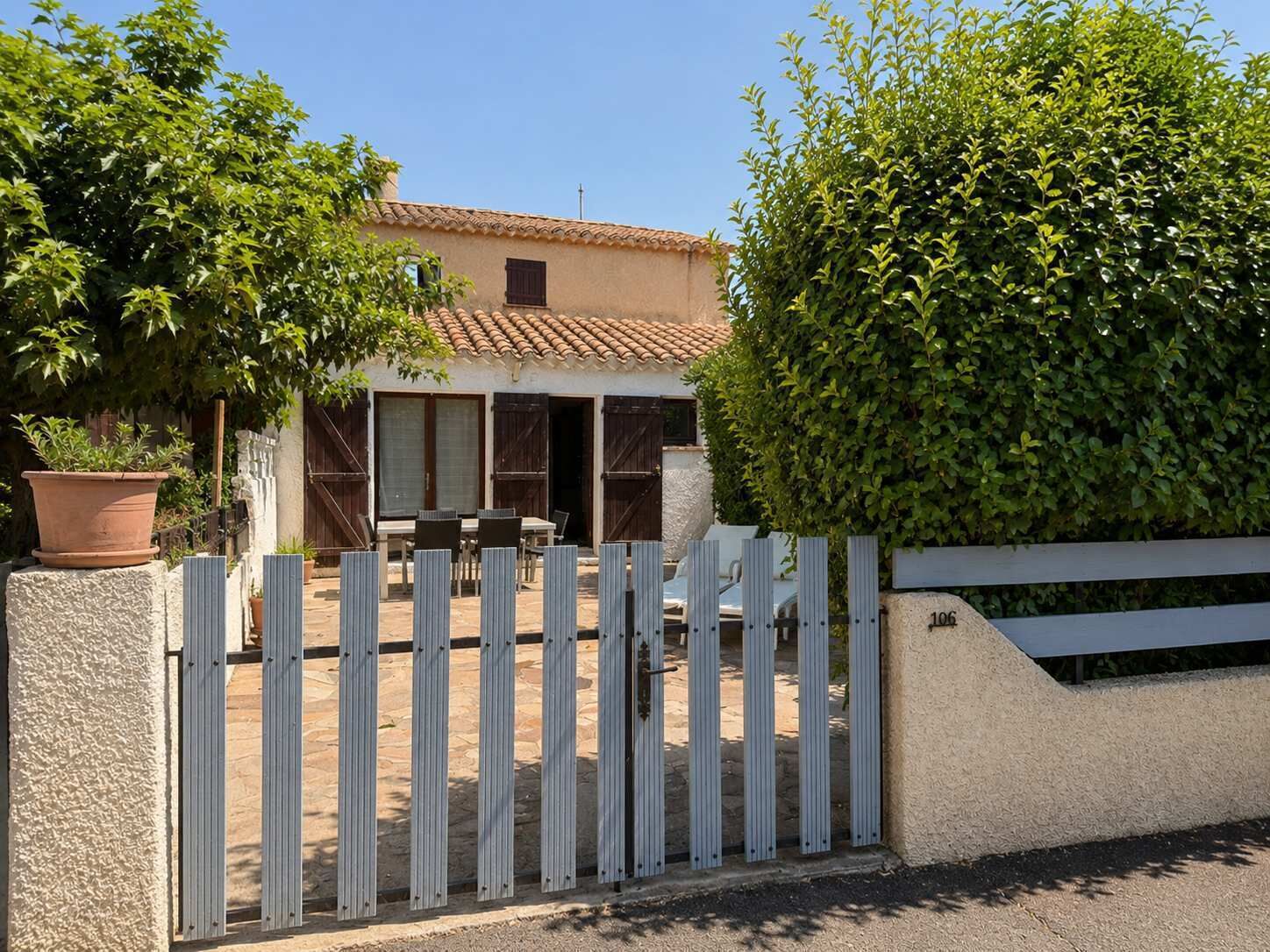 A house with a tiled roof, a fenced patio, and a large bush.