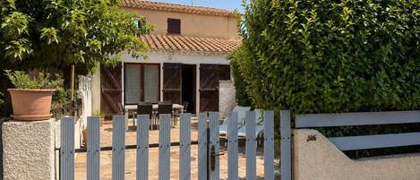 A house with a tiled roof, a fenced patio, and a large bush.