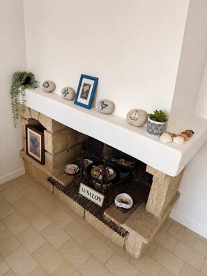 A fireplace with a stone mantle, a framed picture, and decorative shells. - Mediterranean villa – Walking distance to the beach – 2 terraces (Vendres)