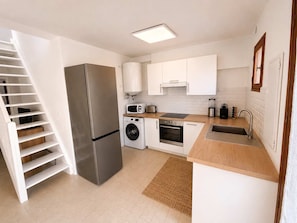A modern kitchen with stainless steel appliances, white cabinetry, and a wooden countertop. - Mediterranean villa – Walking distance to the beach – 2 terraces (Vendres)