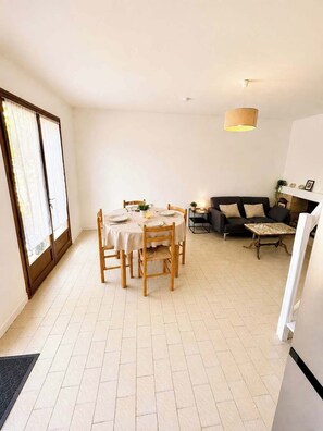 A dining area with a round table and chairs, a sofa, a fireplace, and a refrigerator. - Mediterranean villa – Walking distance to the beach – 2 terraces (Vendres)