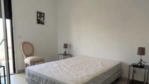 A hotel room with a bed, two bedside tables, a chair, and a wall-mounted picture. - Valras- Loc Archipel Panarea  vue mer (Valras-Plage)