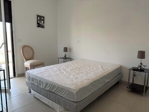 Ein Hotelzimmer mit einem Bett, zwei Nachttischen, einem Sessel und einem Wandbild.