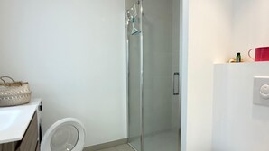 A modern bathroom with a glass shower enclosure, a toilet, and a sink. - Valras- Loc Archipel Panarea  vue mer (Valras-Plage)