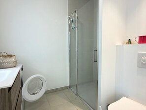 Ein modernes Badezimmer mit Glasdusche, Toilette und Waschbecken.