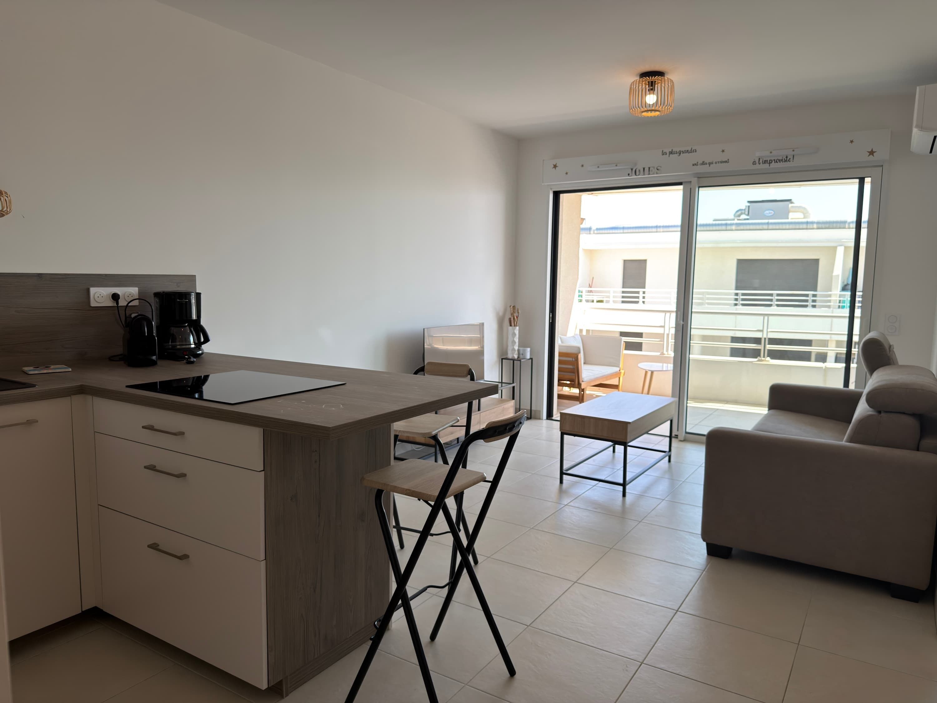 A modern kitchen with a built-in stove, a coffee maker, and a dining area with a table and chairs.