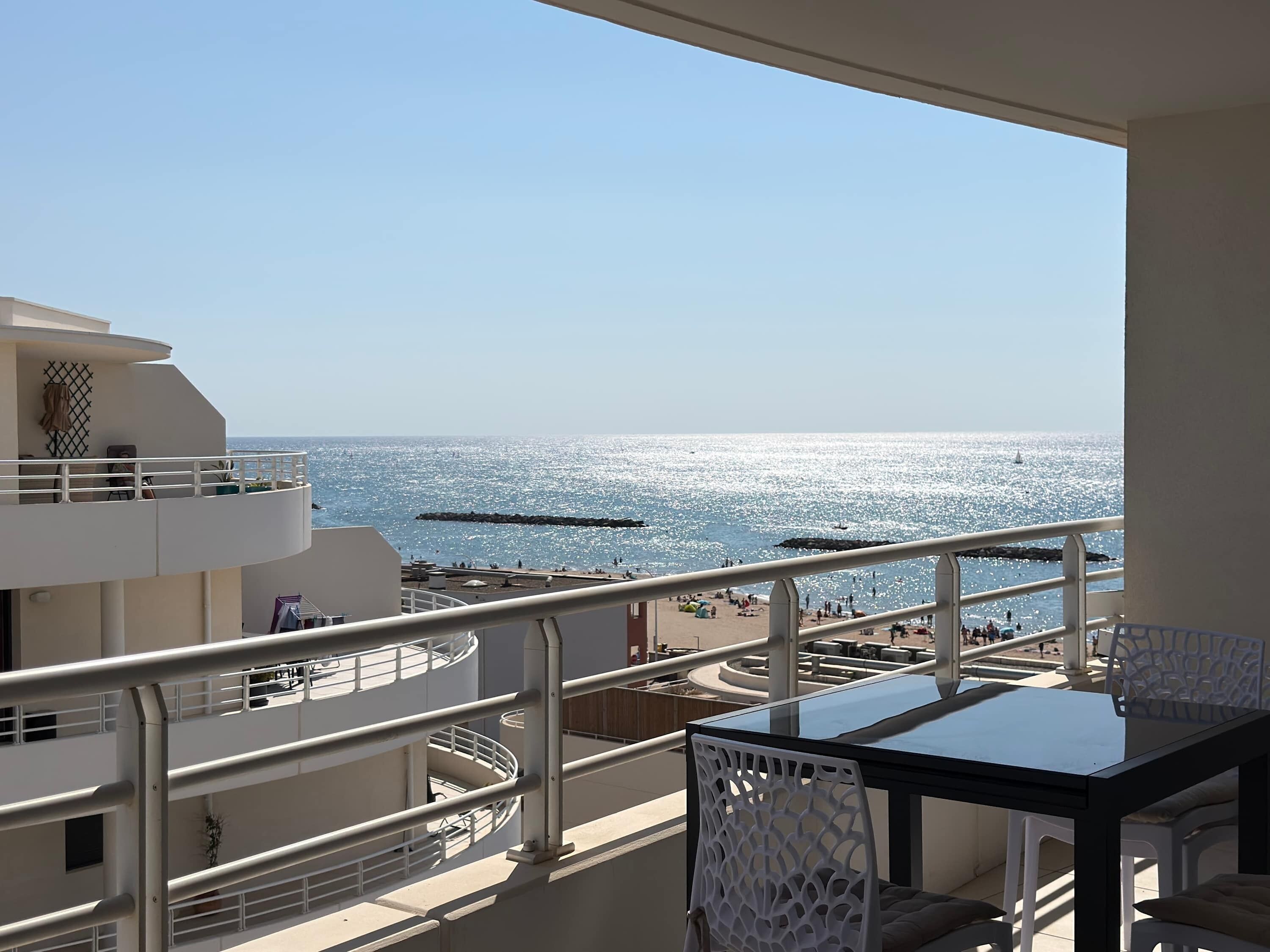 Un balcon avec vue sur la mer, une table et des chaises.