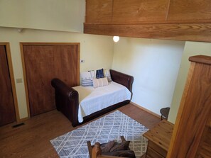 Ein Schlafzimmer mit einem Bett, einem Holzschrank, einem kleinen Holztisch und einem gemusterten Teppich.