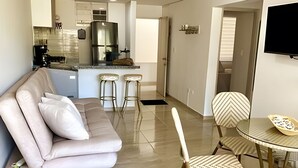 A living room with a sofa, two chairs, a dining table, and a kitchen area in the background. - Rodadero Relax | Walk to Beach & Park (Santa Marta)